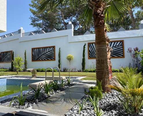 Kuşadası’nda villa bahçesinde yapılan peyzaj tasarımı ve uygulaması, yürüyüş yolları, oturma alanları ve lazer kesim duvar panosu örneği